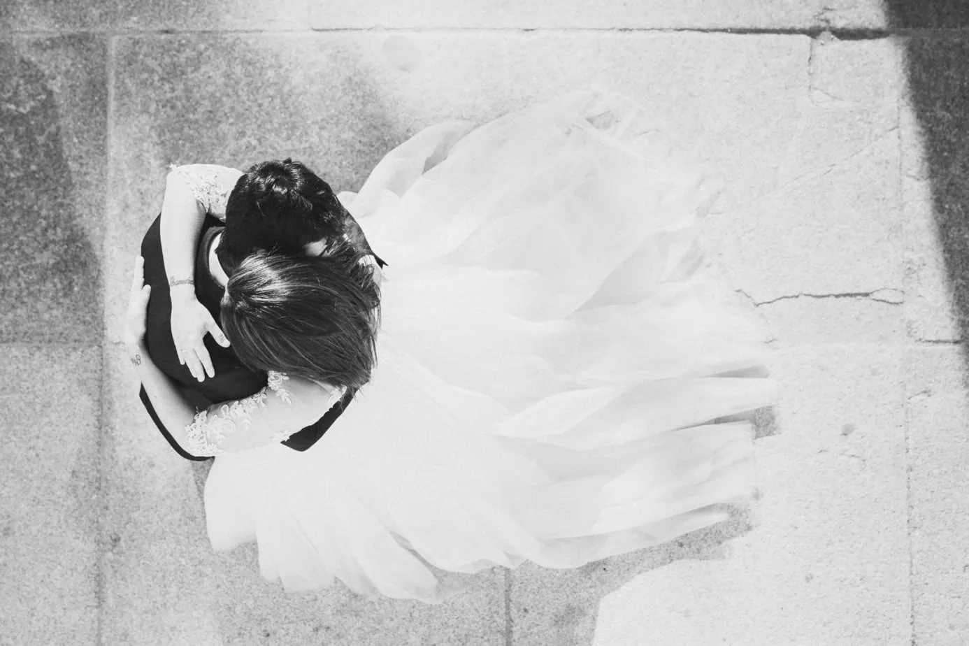 Dos personas abrazadas en ropa formal, vestido largo, vista superior en blanco y negro.